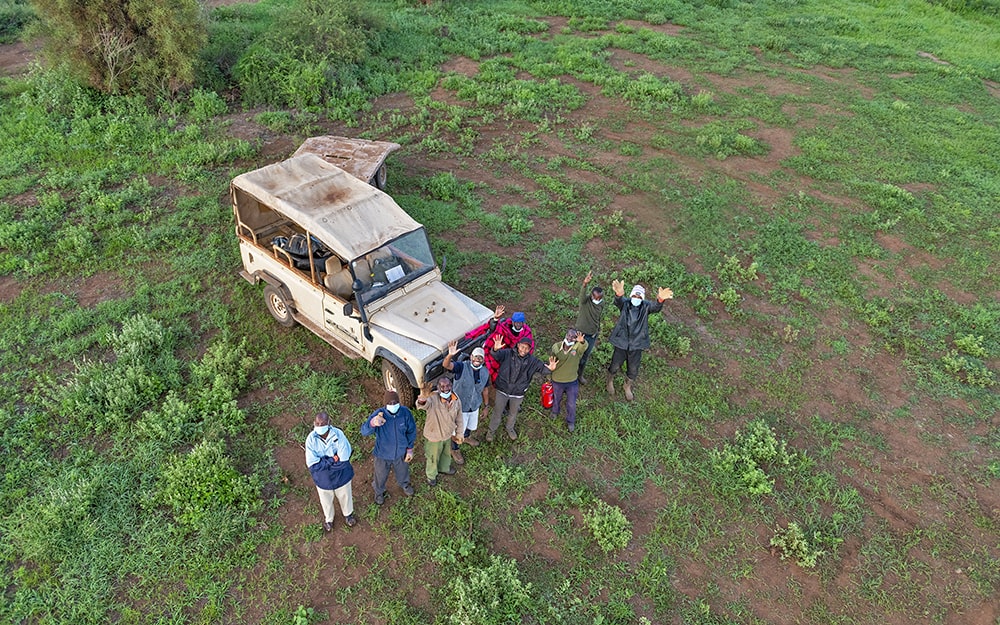 Image of the Kilimanjaro Balloon Safari team waving from the ground at guests in the balloon safari experience at Tulia Amboseli Safari Camp