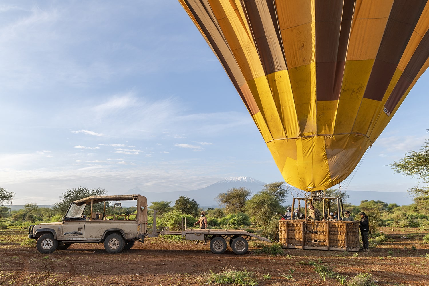 Image of a hot air balloon of a balloon safari and a classic land rover by Kilimanjaro Balloon Safaris