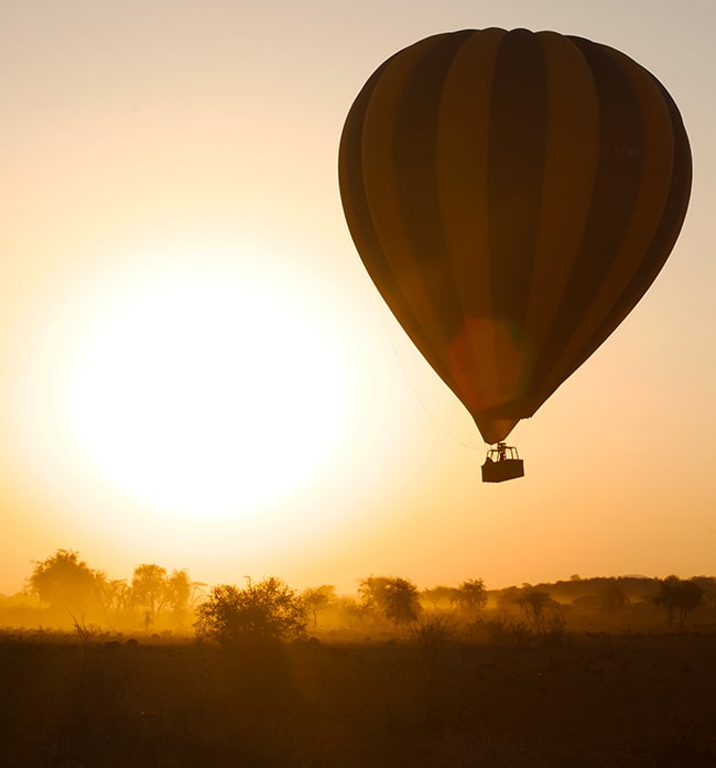 Image of the sun rising and the Kilimanjaro Balloon Safari balloon rising from the ground at Amboseli National Park, Kenya